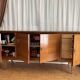 Vintage 4-door buffet with wood veneer and glass top.