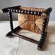 Antique wooden turned spool footrest with straw.