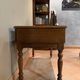 Antique carved wooden bench with green upholstered seat and backrest.