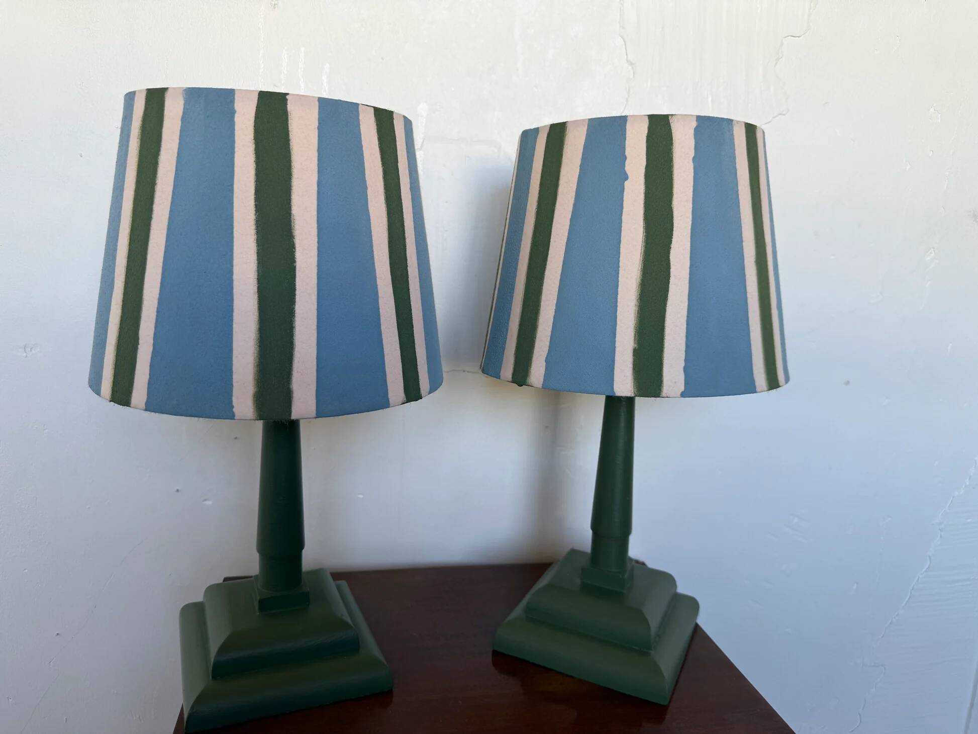 Pair of vintage wooden lamps with their striped beige, blue, and green shades.