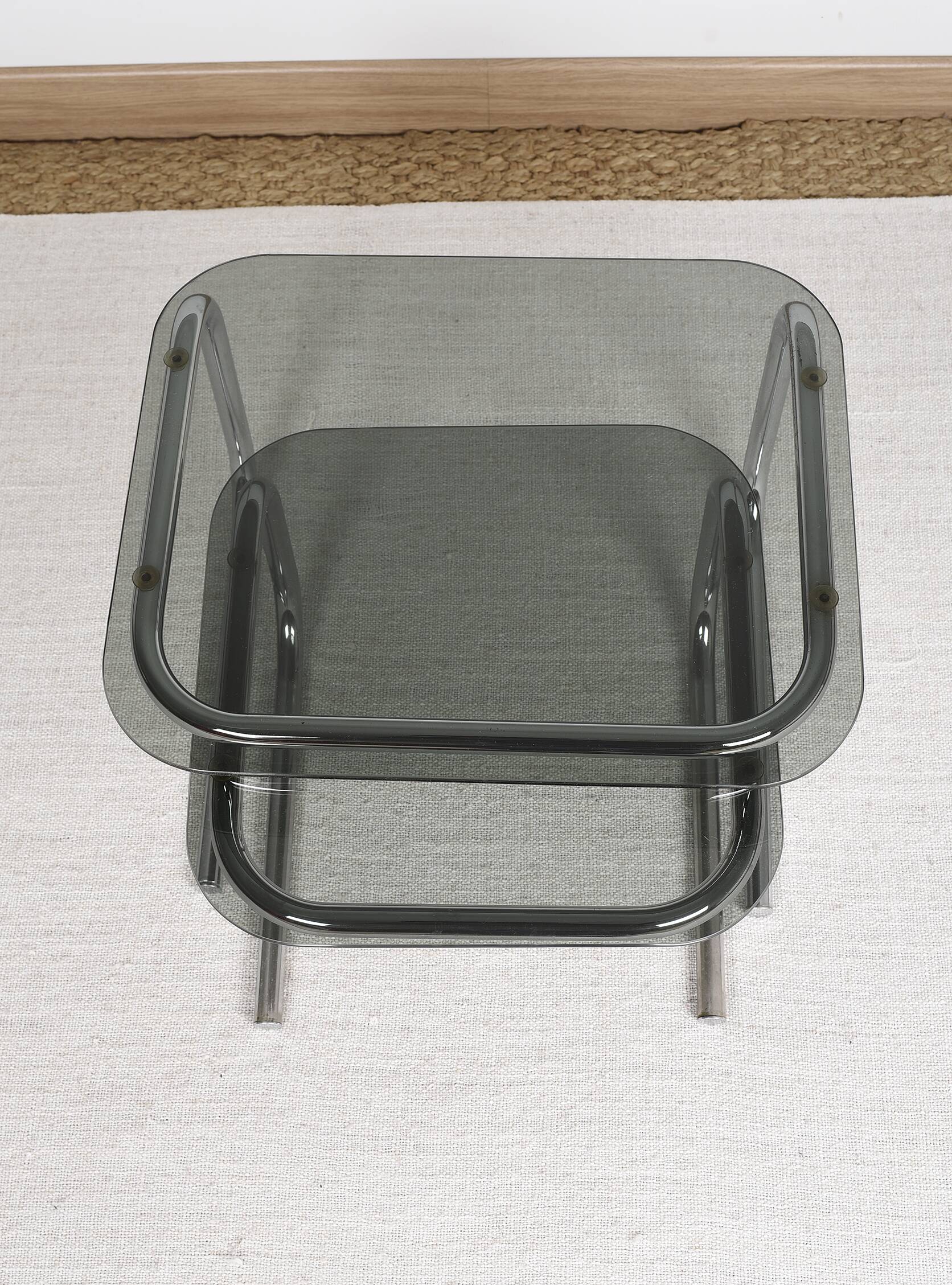 Pair of nesting tables in smoked glass and chrome legs.