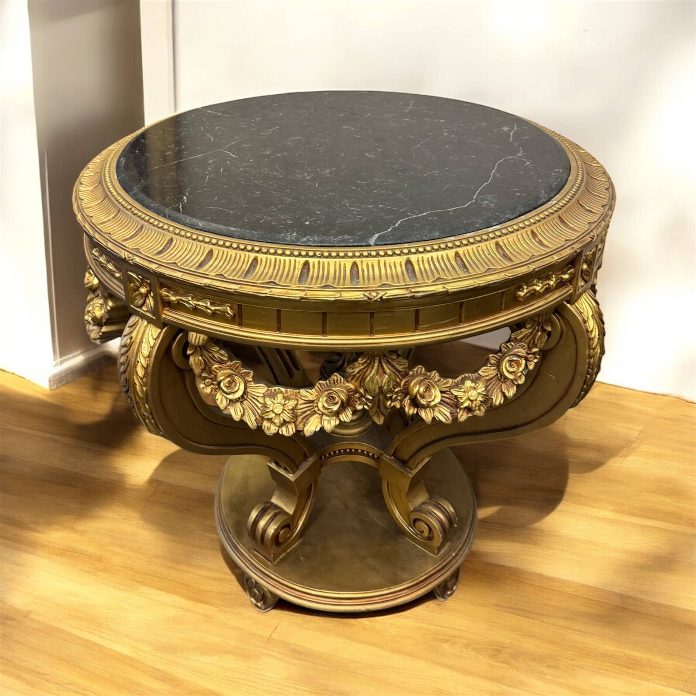 A round Louis XV style table in carved gilt beechwood with a black marble top