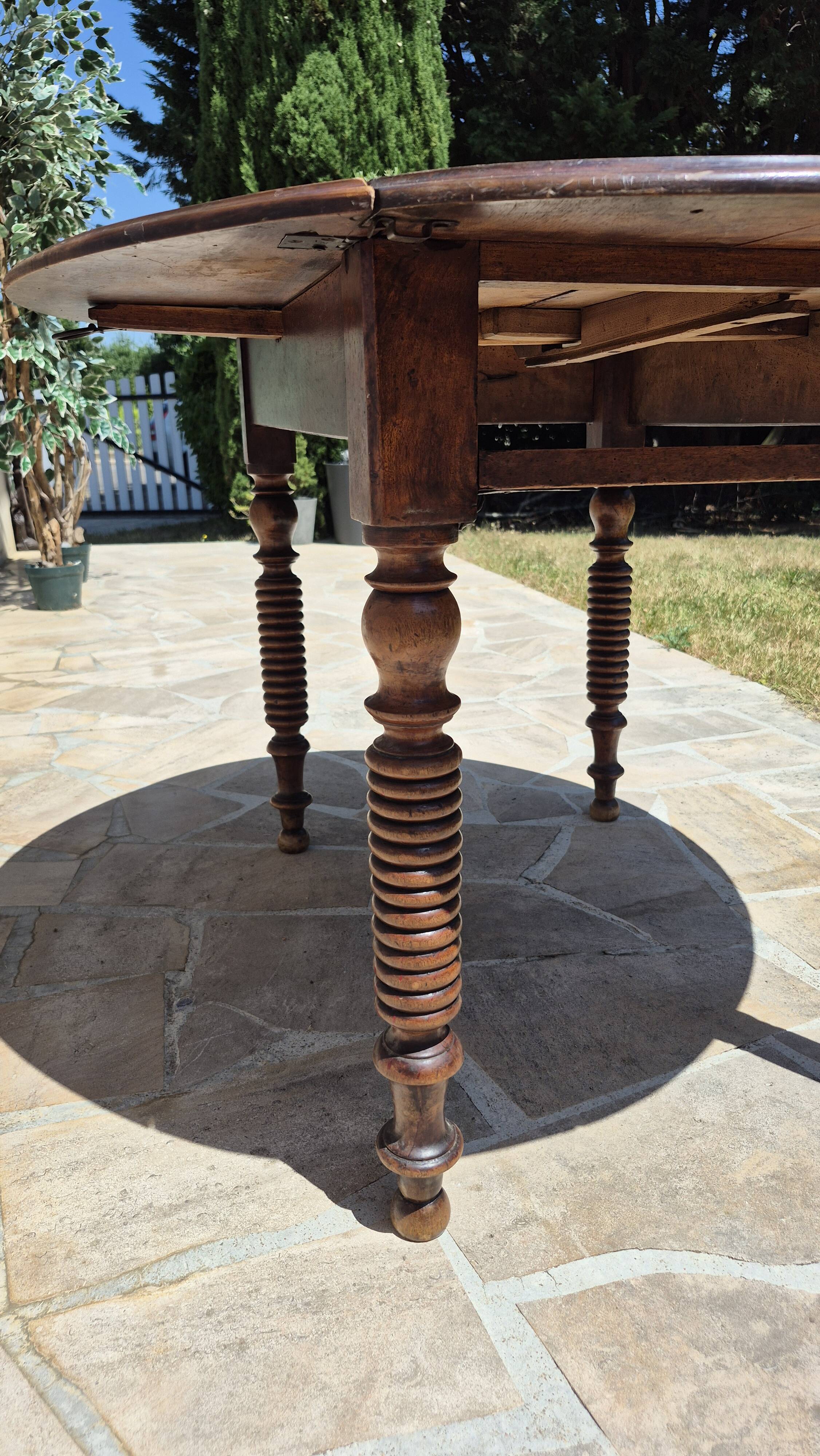 Round dining table with a drop-leaf top in solid walnut, late 19th century.