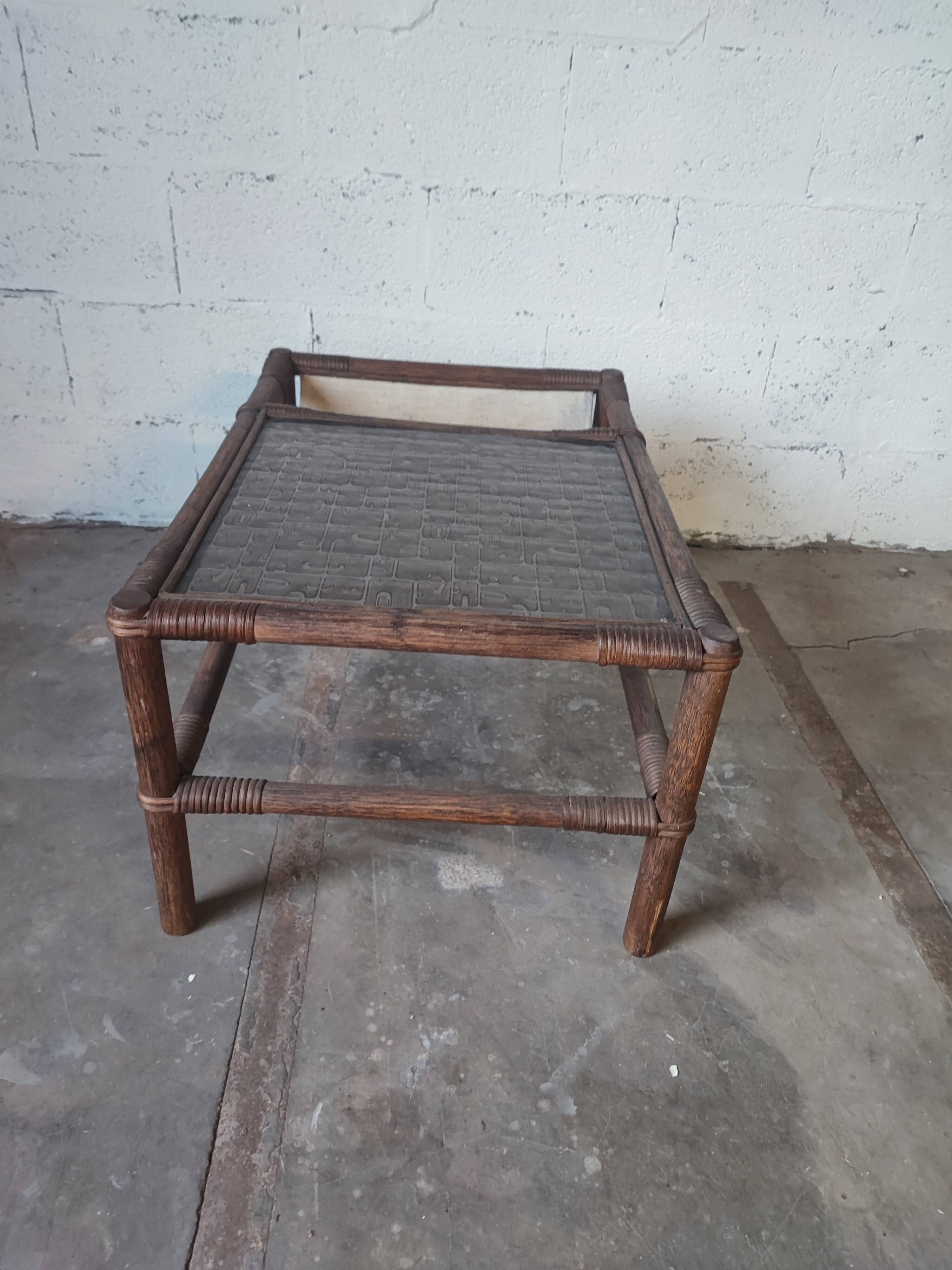 Relaxed armchair in bamboo and rattan with its small side table. Beige linen cushion.