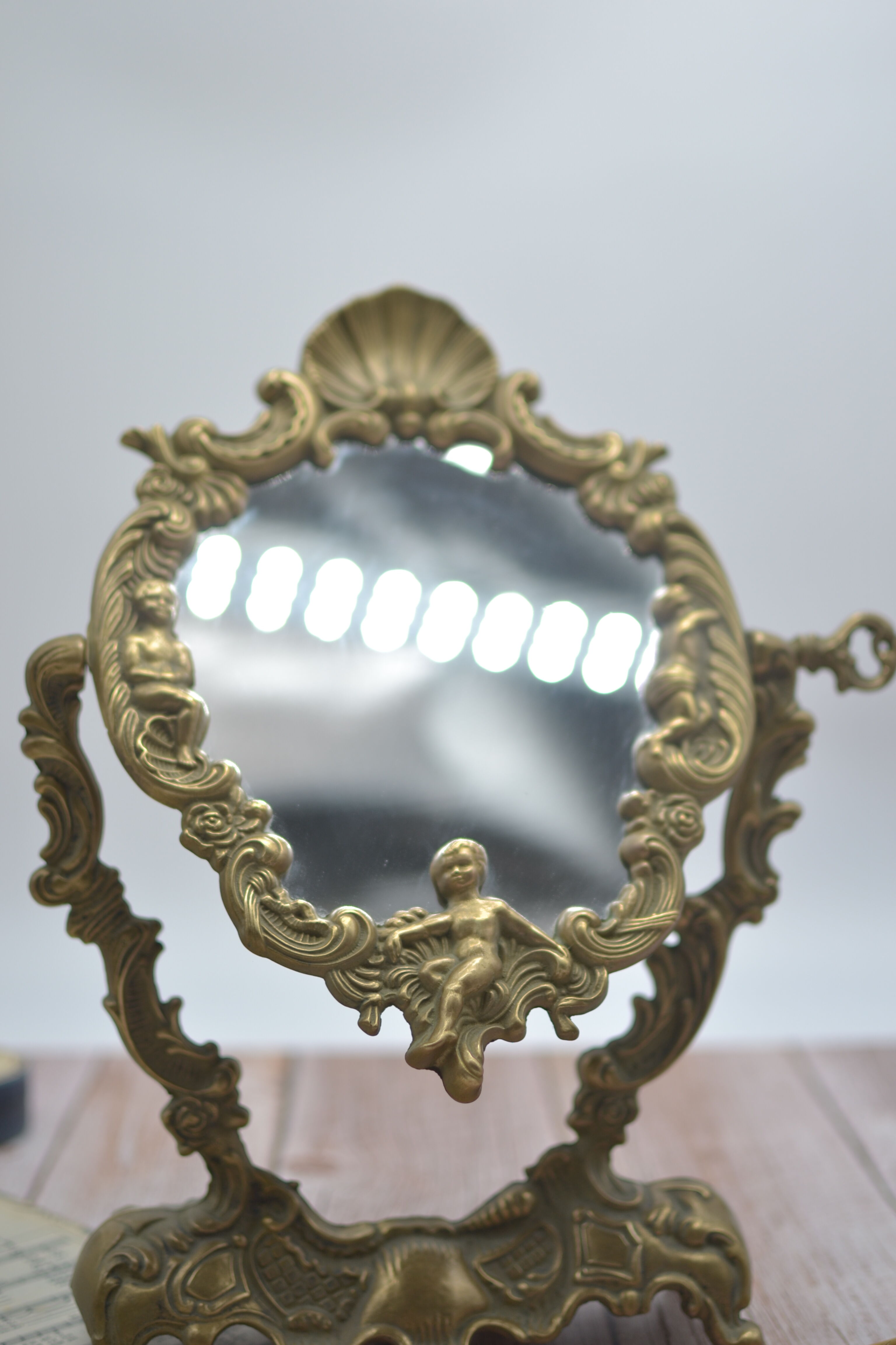 Adjustable psyche mirror of 33 centimeters in gilded bronze with angel ornament