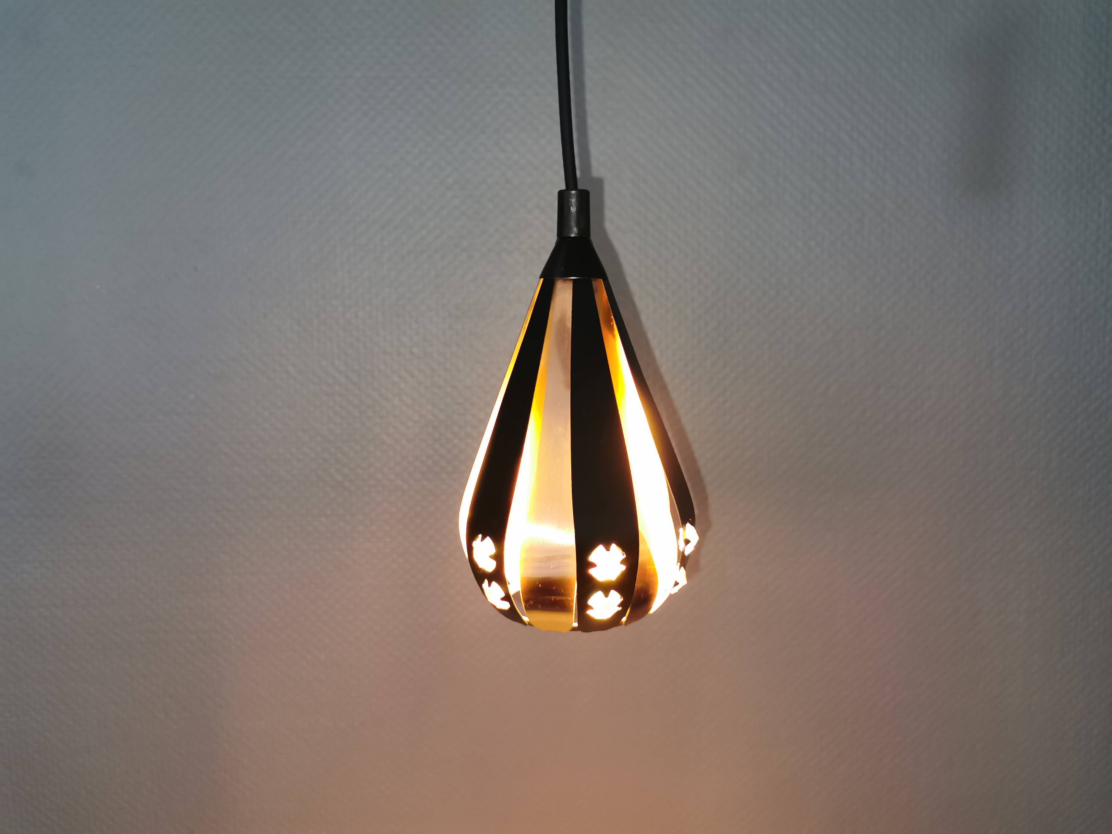 A teardrop-shaped pendant lamp made of copper, black metal, and prisms.