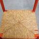 Vintage 1970s red wooden chair with a woven wicker seat