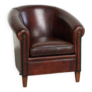 Vintage sheepskin club armchair with decorative nails and black piping
