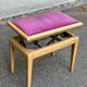 Adjustable piano stool in light beech and purple velvet.