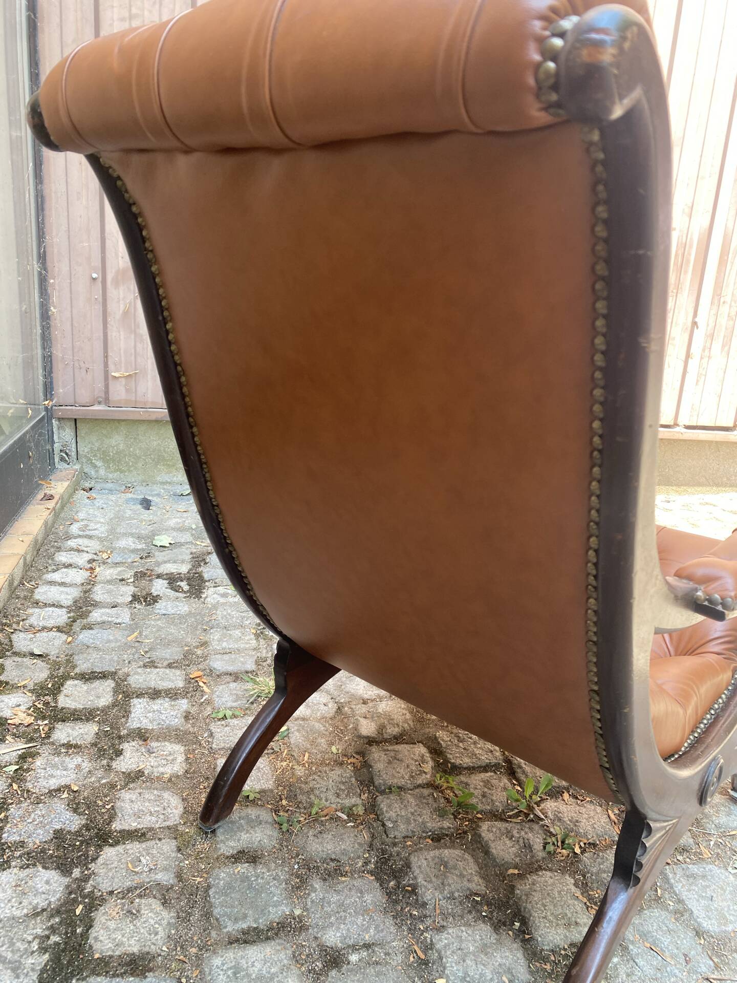 Chesterfield armchair in leather and carved solid wood