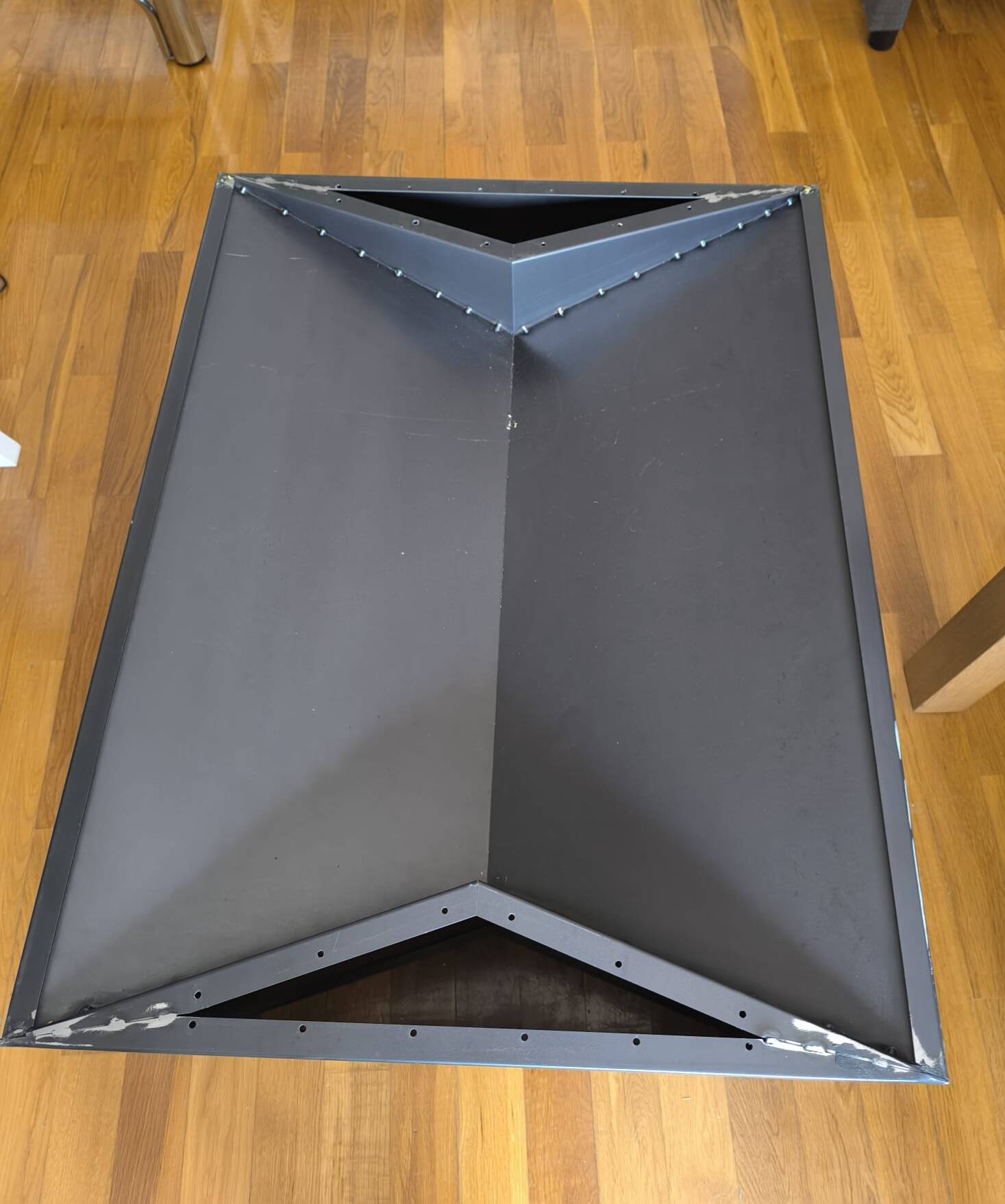 Minimalist/industrial coffee table with a black metal frame and a grey fabric top.