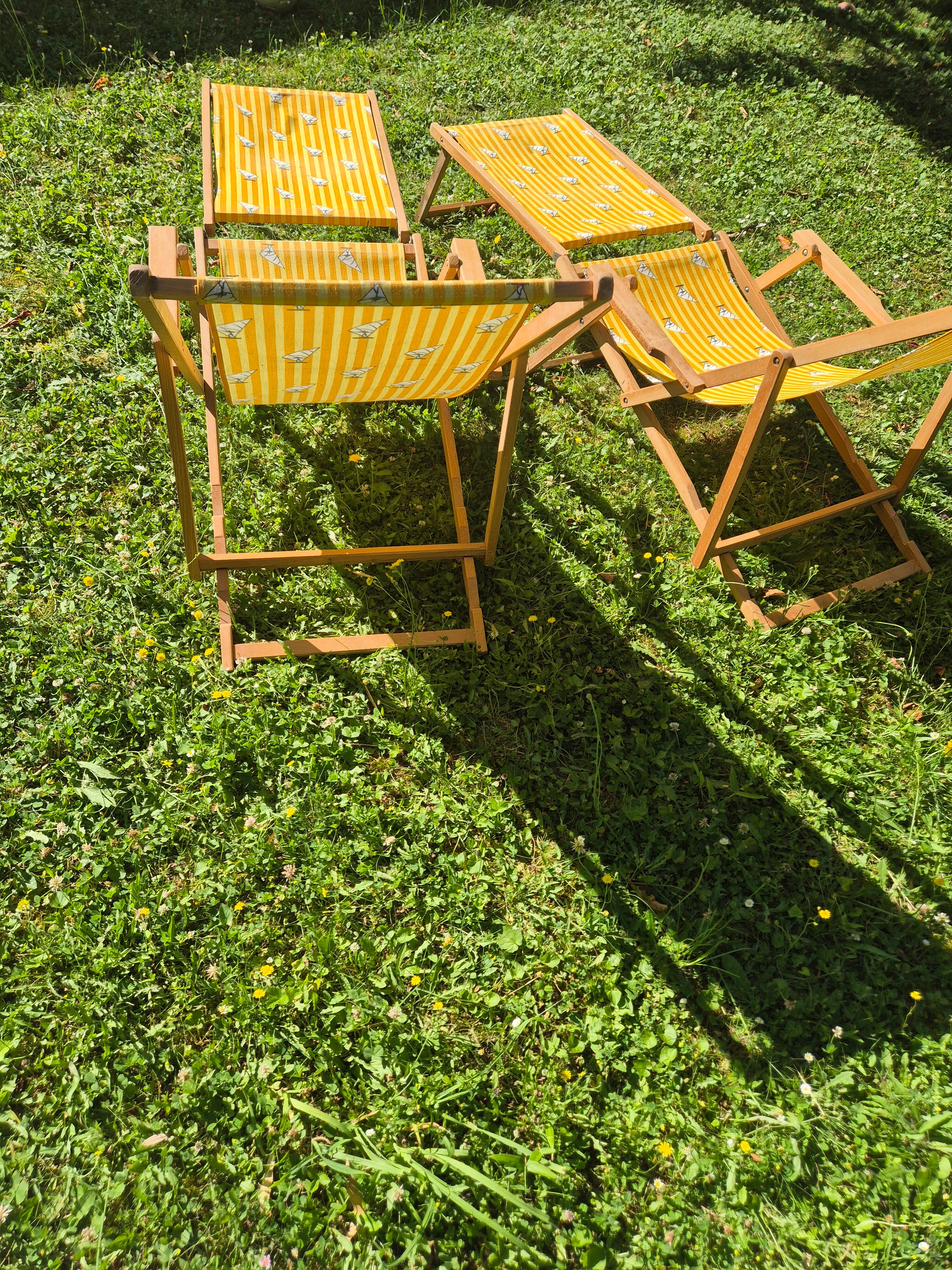 2 vintage Chilean deck chairs made of wood and yellow fabric printed with sailboats, with footrests.