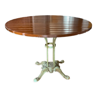 Round table in varnished brown stained wood, green tinted cast iron foot