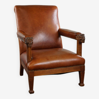 Armchair with lion heads reupholstered in cognac-colored cowhide