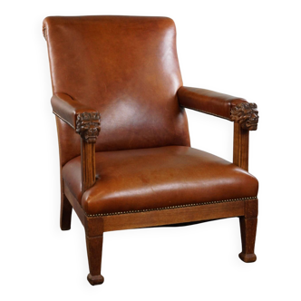 Armchair with lion heads reupholstered in cognac-colored cowhide