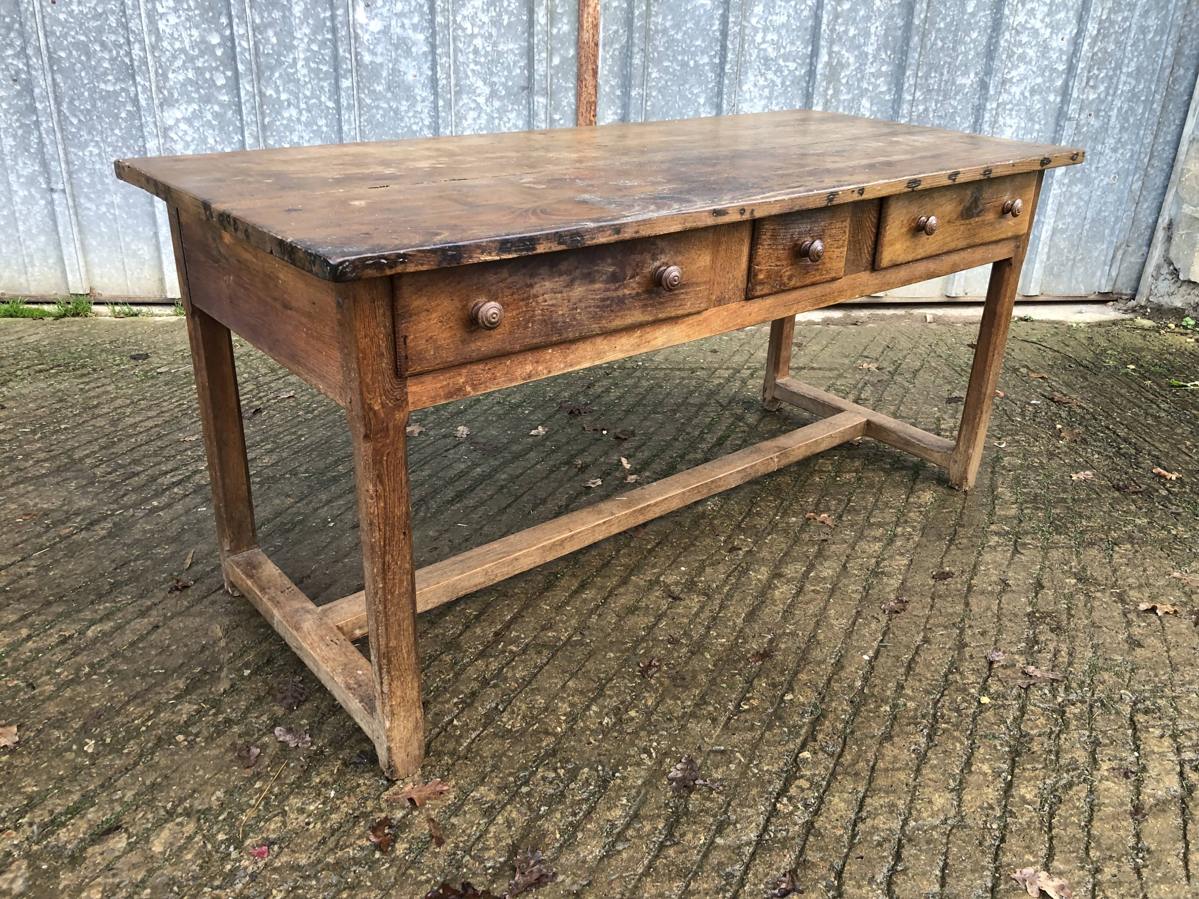 Old chestnut table with 3 front drawers and a cat bar.
