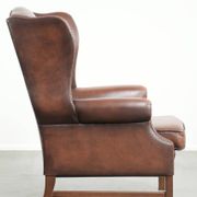Fauteuil à oreilles en cuir de vache confortable de style anglais avec un look intemporel.