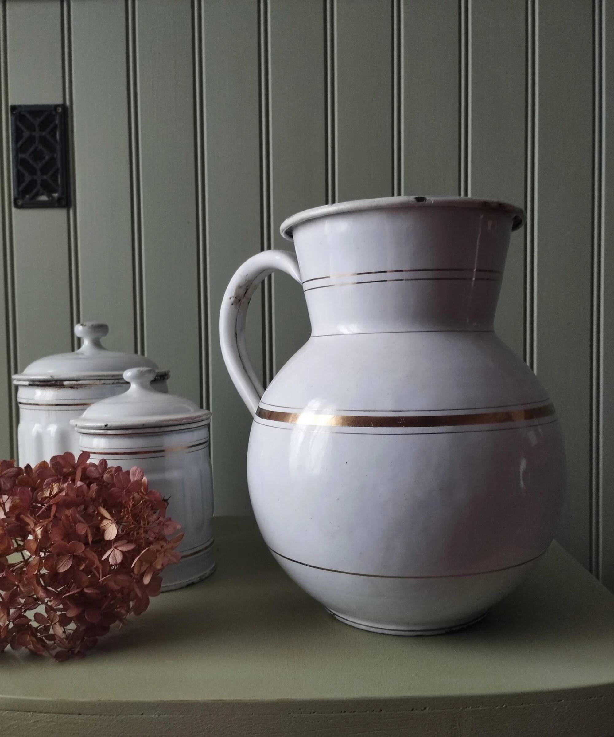 Old enamelled metal jug with gold trim.