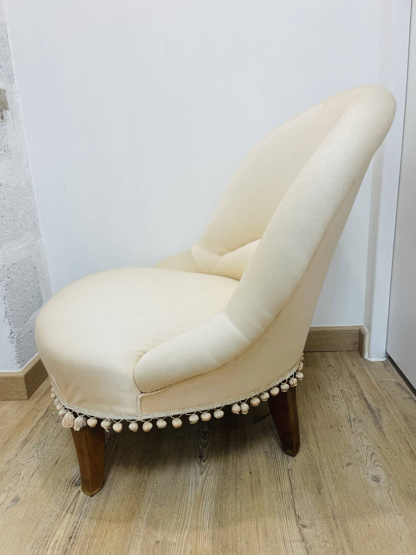 Pale pink upholstered armchair with wooden legs.