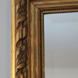 Miroir ancien doré surmonté d'un fronton et glace biseautée