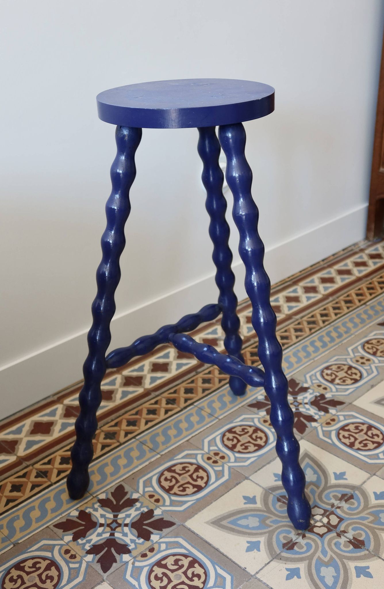 Vintage tripod stool made of turned wood, painted blue.