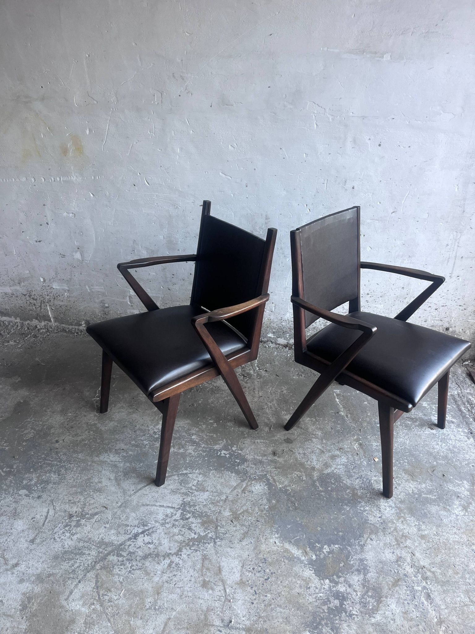 Pair of sculptural mid-century armchairs in dark wood and brown upholstery.