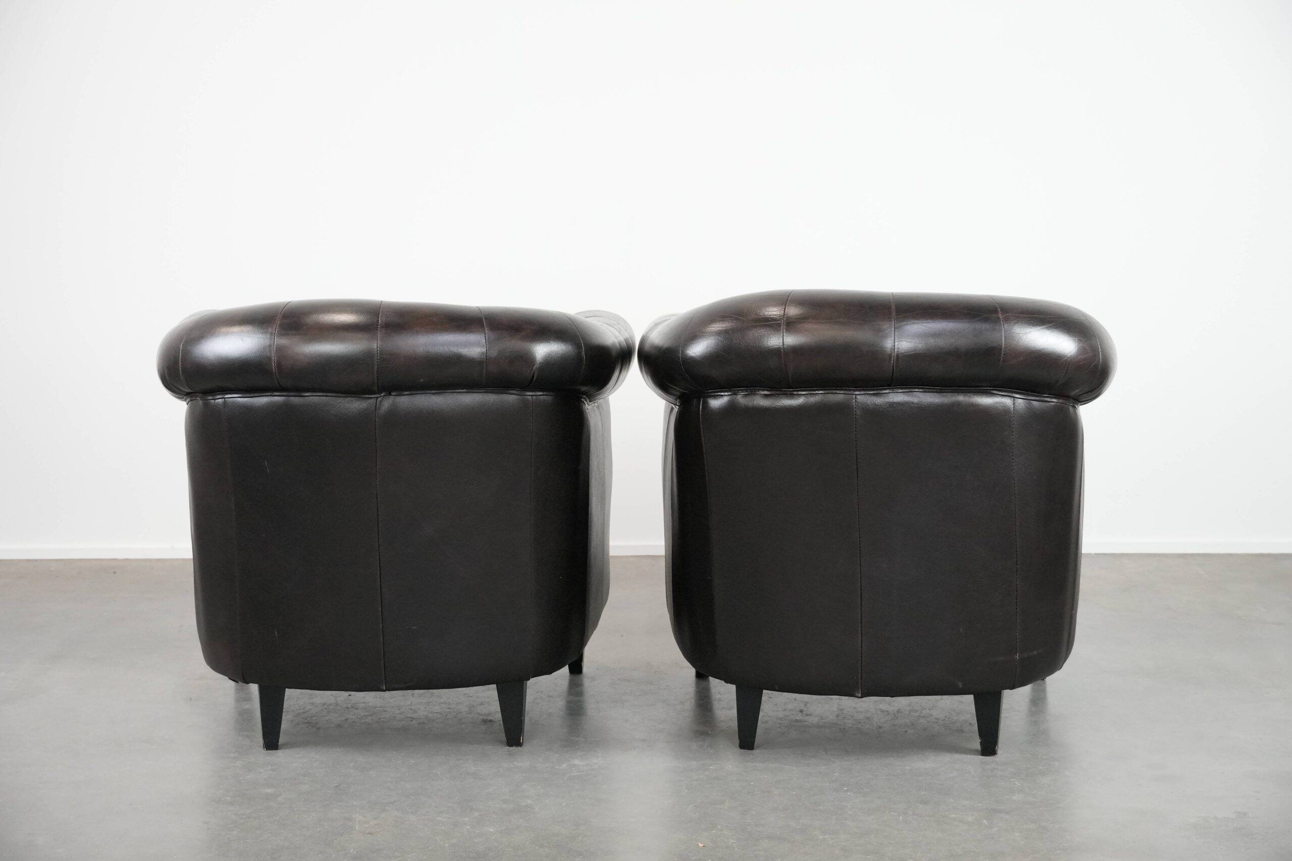 Ensemble de deux luxueux fauteuils club Chesterfield en cuir de vachette noir.