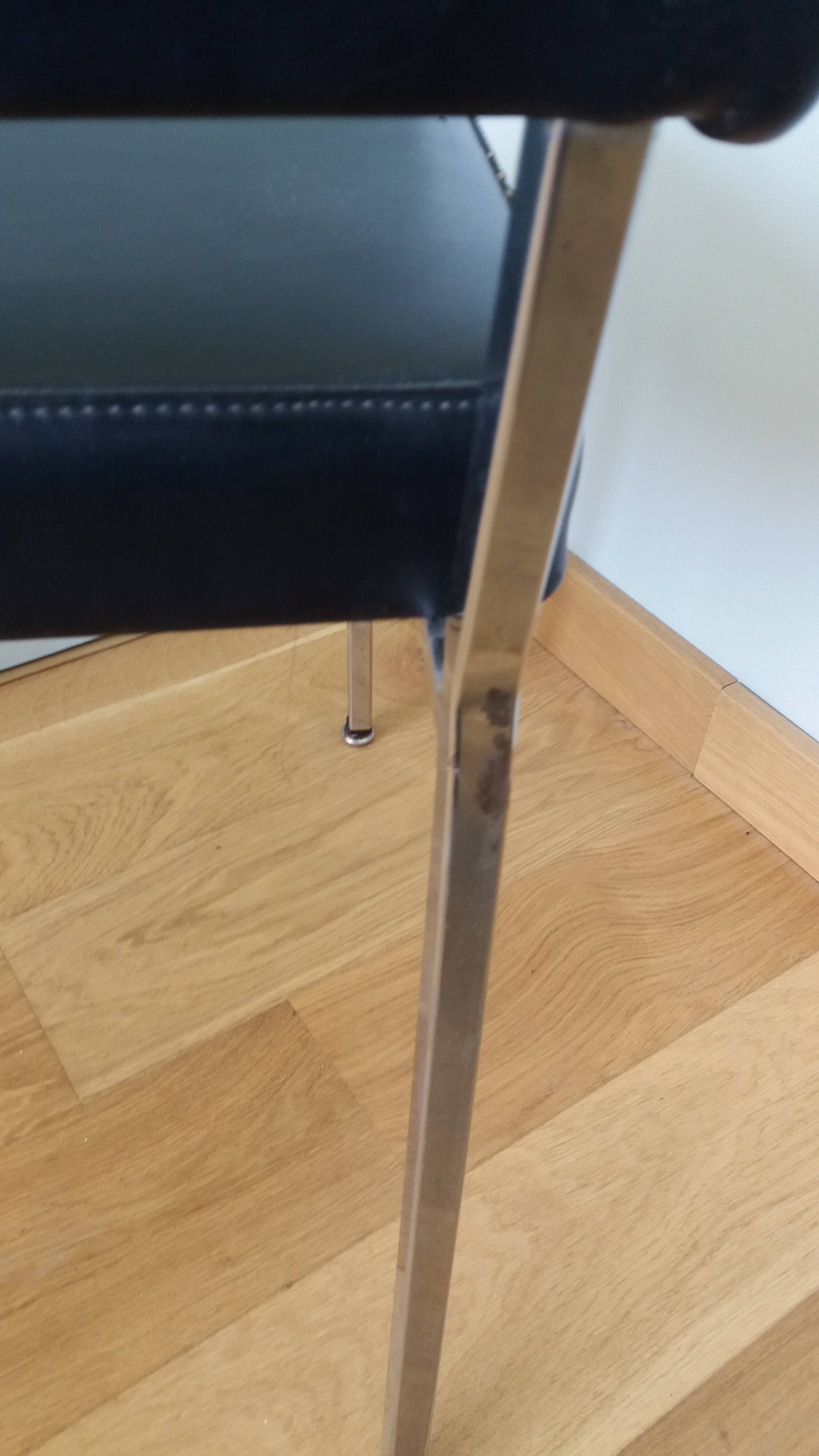 Chrome metal chairs and black faux leather upholstery in retro modernist style.