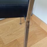 Chrome metal chairs and black faux leather upholstery in retro modernist style.