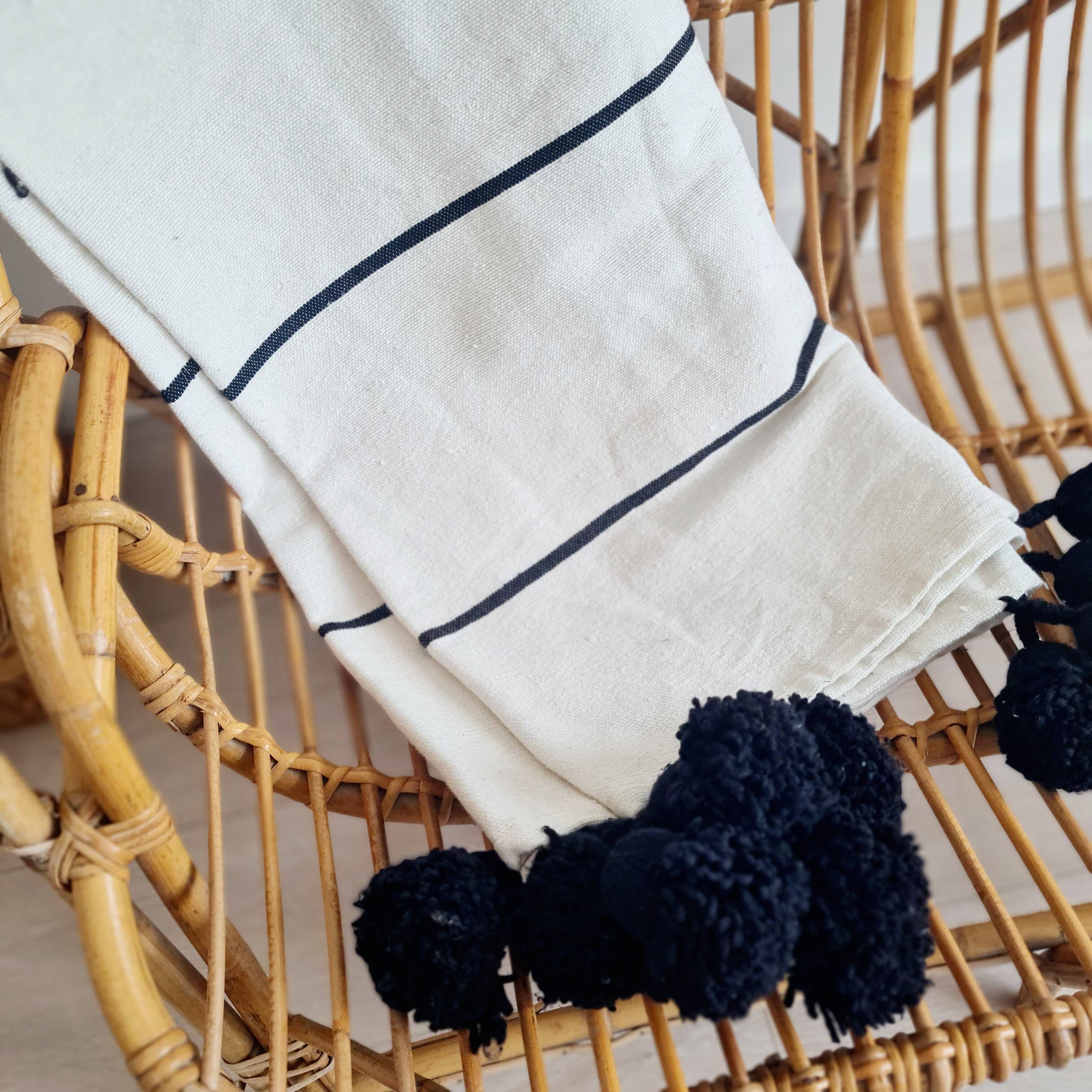 Handwoven throw with black stripes and pom-poms