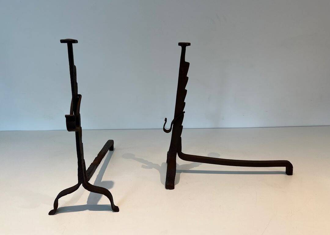Pair of wrought iron andirons with adjustable supports and tripod feet.
