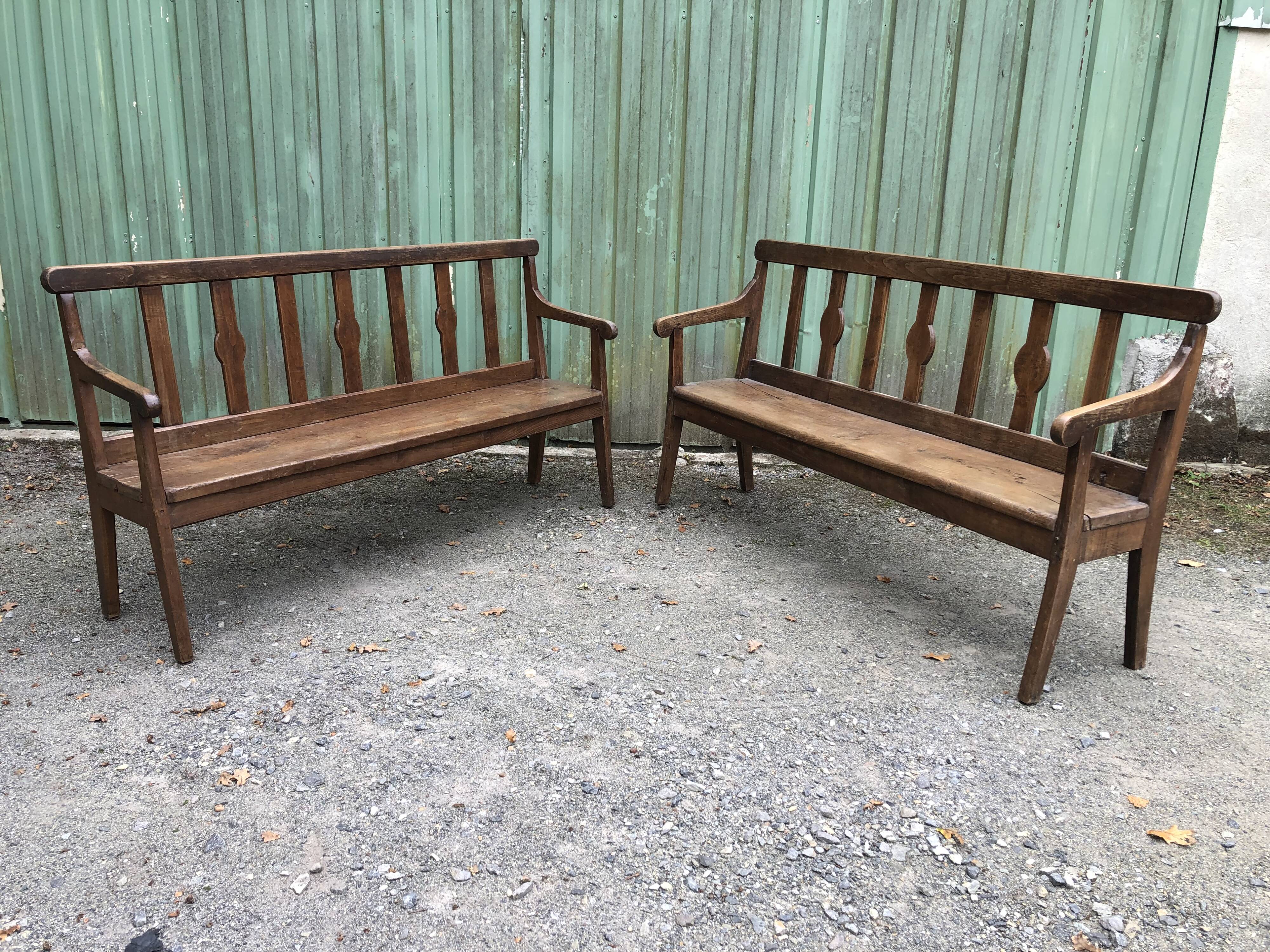 Duo of old solid oak benches with backs and armrests.