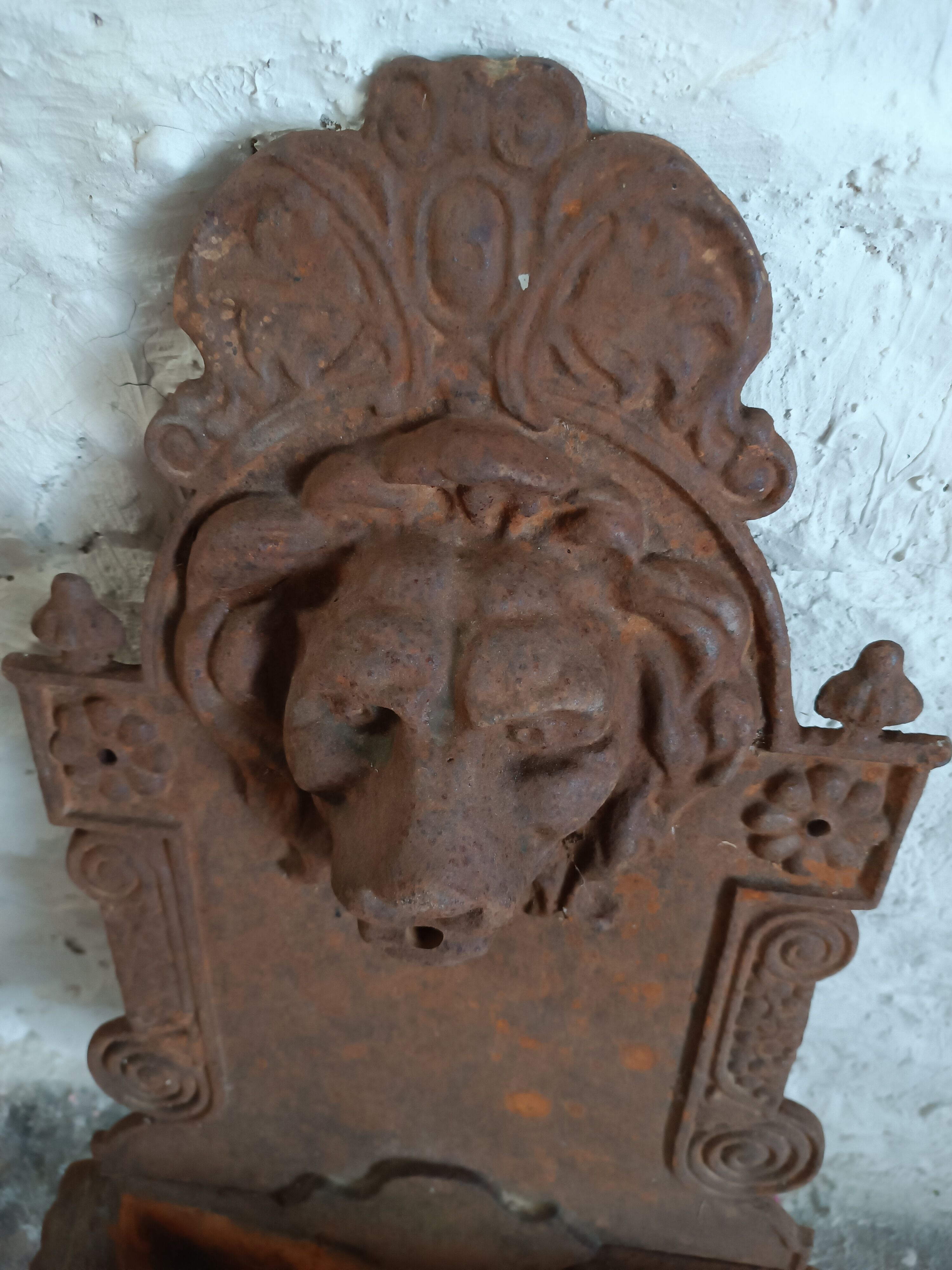Old cast iron wall fountain with lion's head