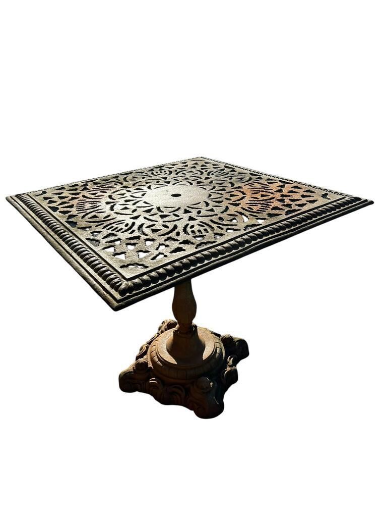 Antique cast iron garden table with decorative openwork top.