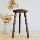 Antique tripod stool with turned wooden legs and leather seat.