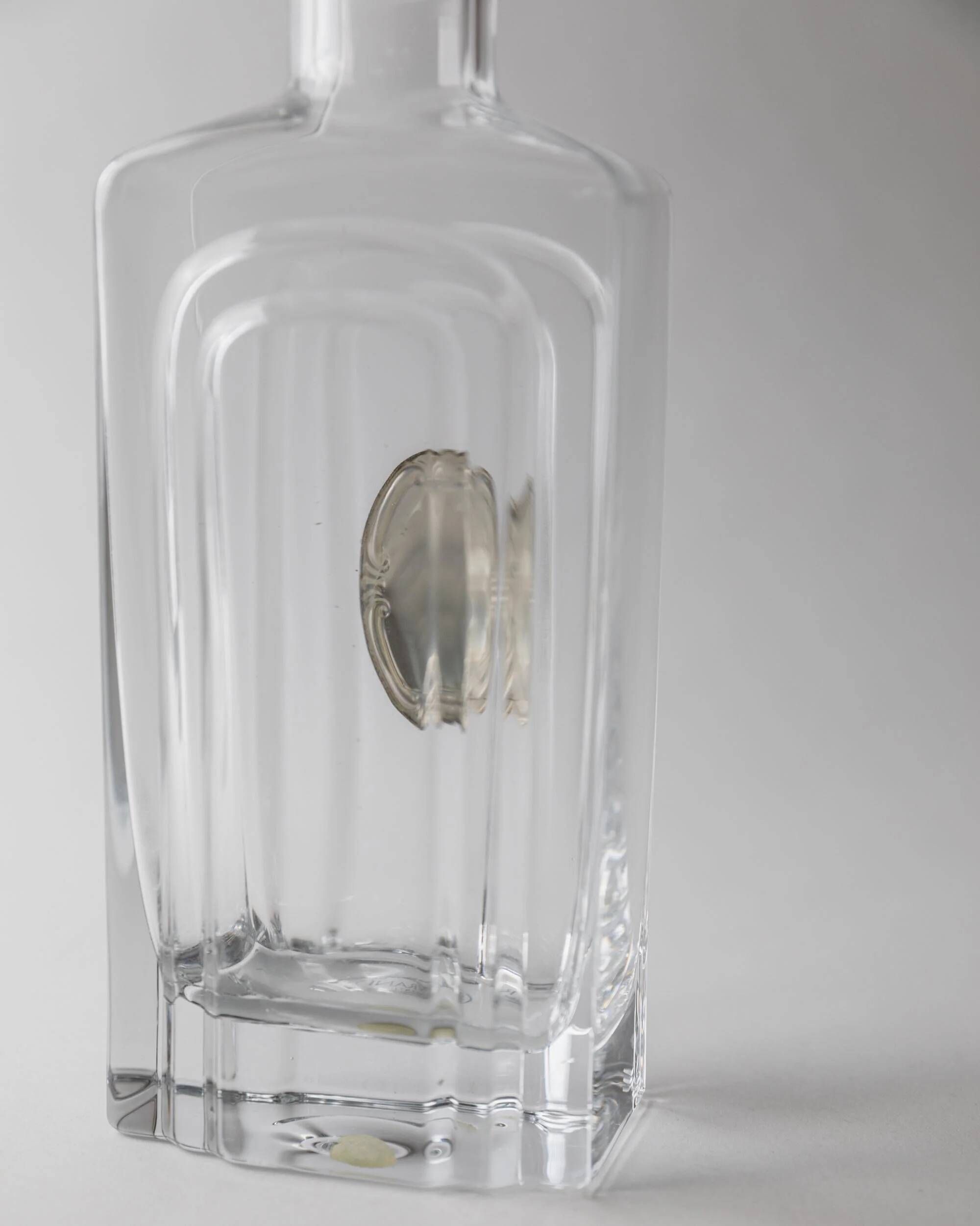 Vintage glass decanter from the 1980s, transparent glass with a silver plate and spherical stopper.