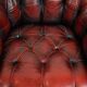 Classic cowhide chesterfield buttonseat armchair in a beautiful red colour and elegant round shapes