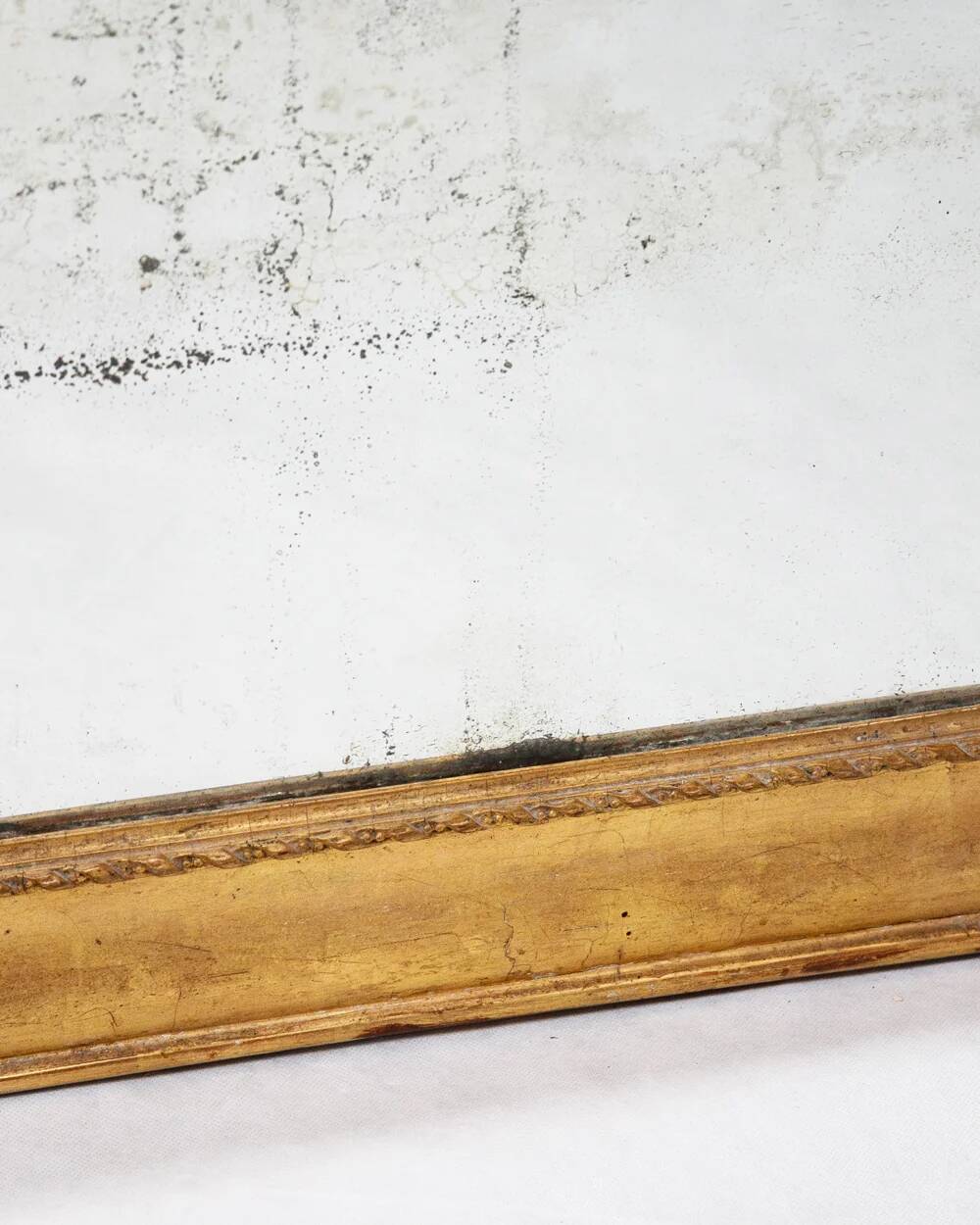 19th-century patinated mirror with a ribbon-style frame