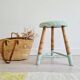 Antique tripod stool with striped seat.