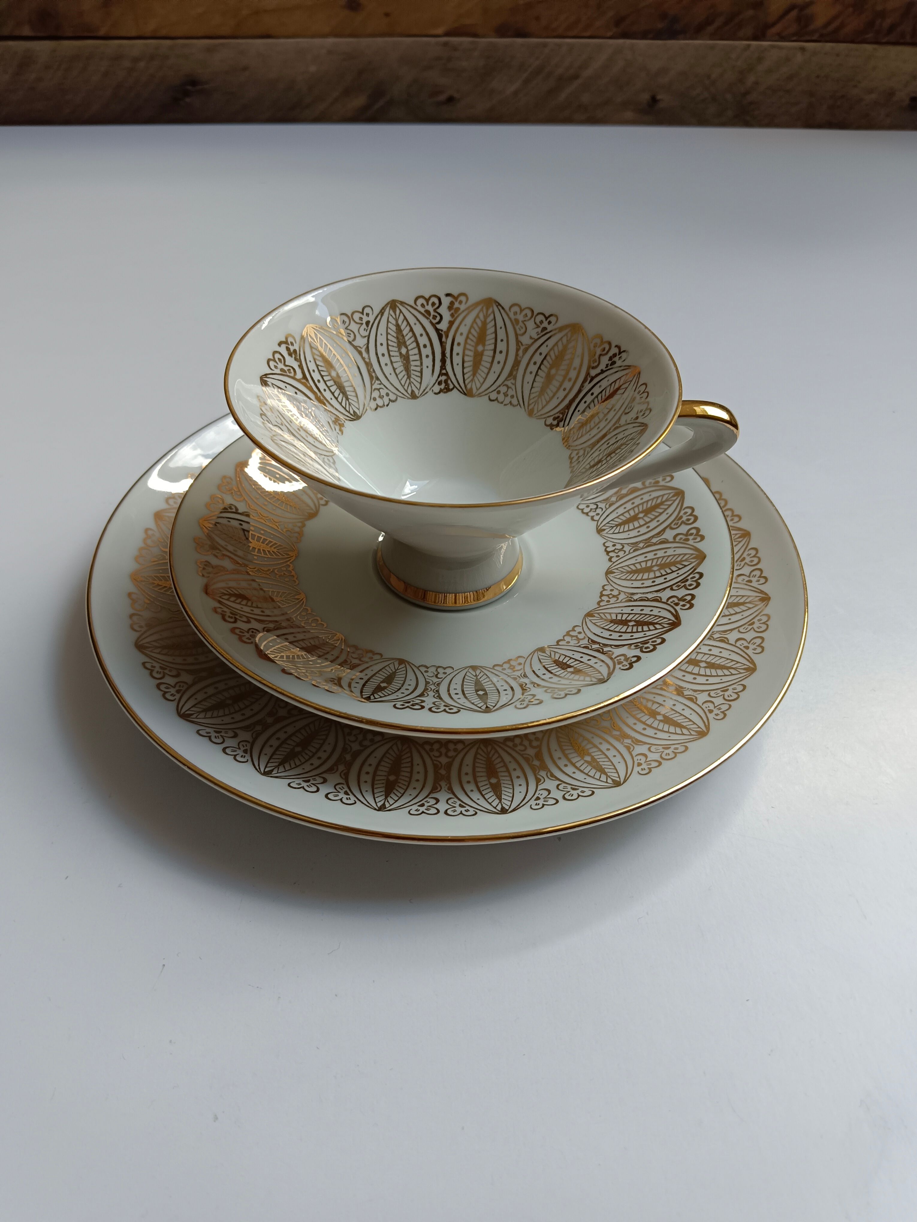Solitaire tea cup, saucer, and dessert plate in white and gold.