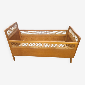 Old vintage baby bed in rattan and wood