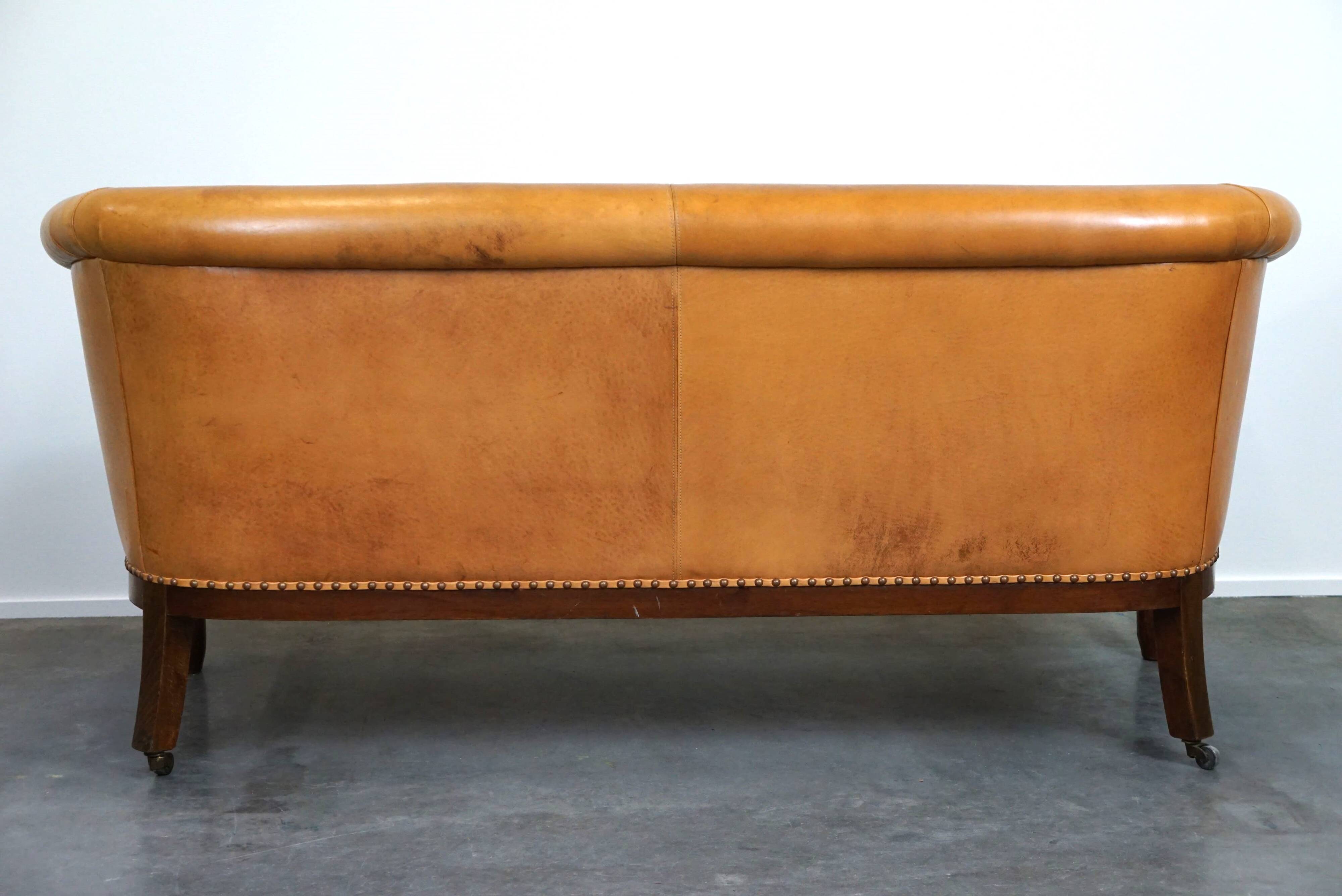 Unique old set of 2 club armchairs and a couch in cognac-colored leather with wheels