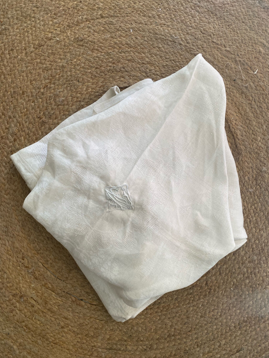 Damask tablecloth with a floral pattern and a central embroidered monogram.