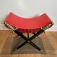 Neoclassical curule stool in red leather, decorated with crossed swords in bronze and metal covered in black leather.