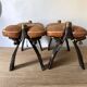 Pair of low Egyptian stools, camel saddles in wood, leather and brass