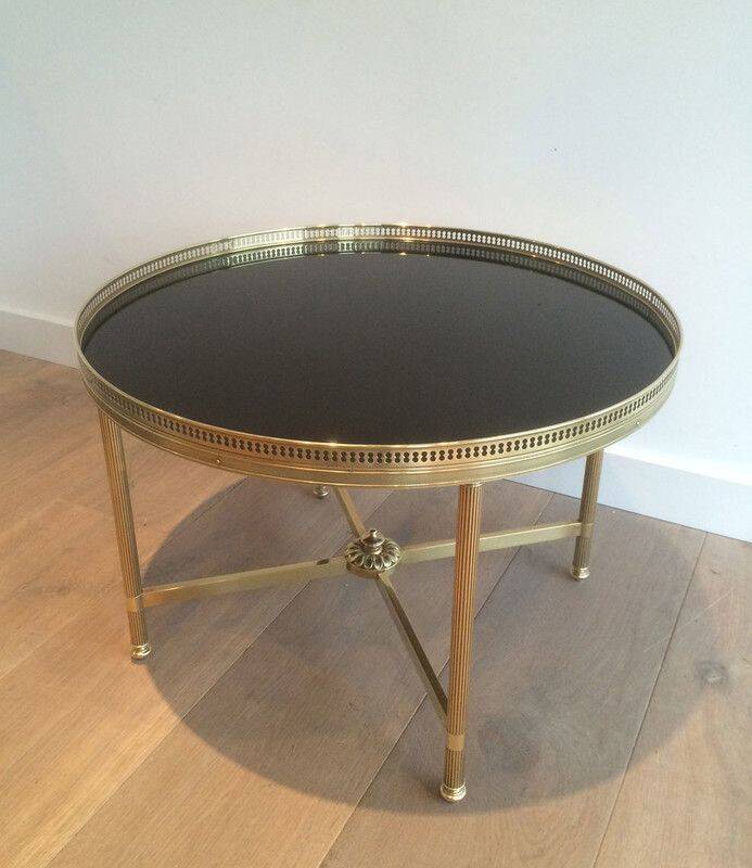 Round coffee table in brass with a black lacquered glass top by Maison Jansen.