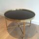 Round coffee table in brass with a black lacquered glass top by Maison Jansen.
