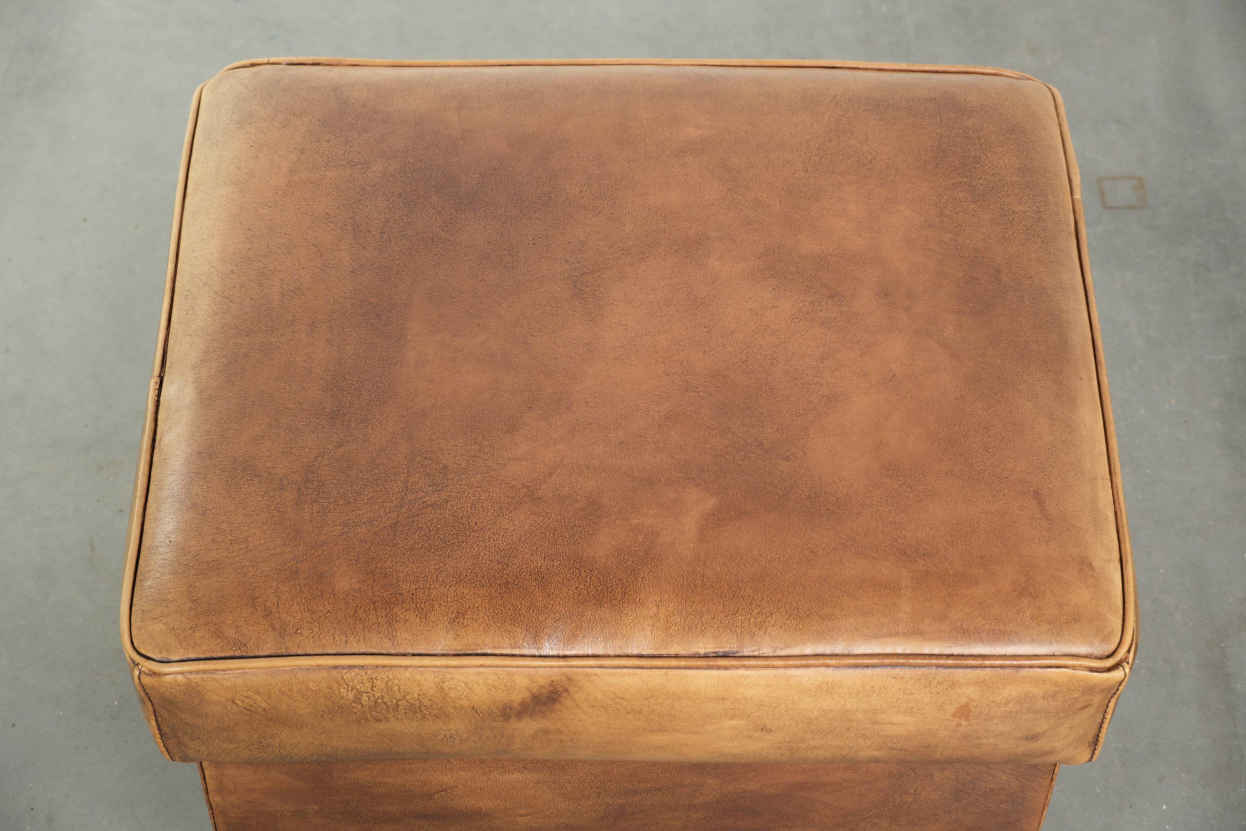 Cowhide ottoman with a beautiful patina finished with decorative nails