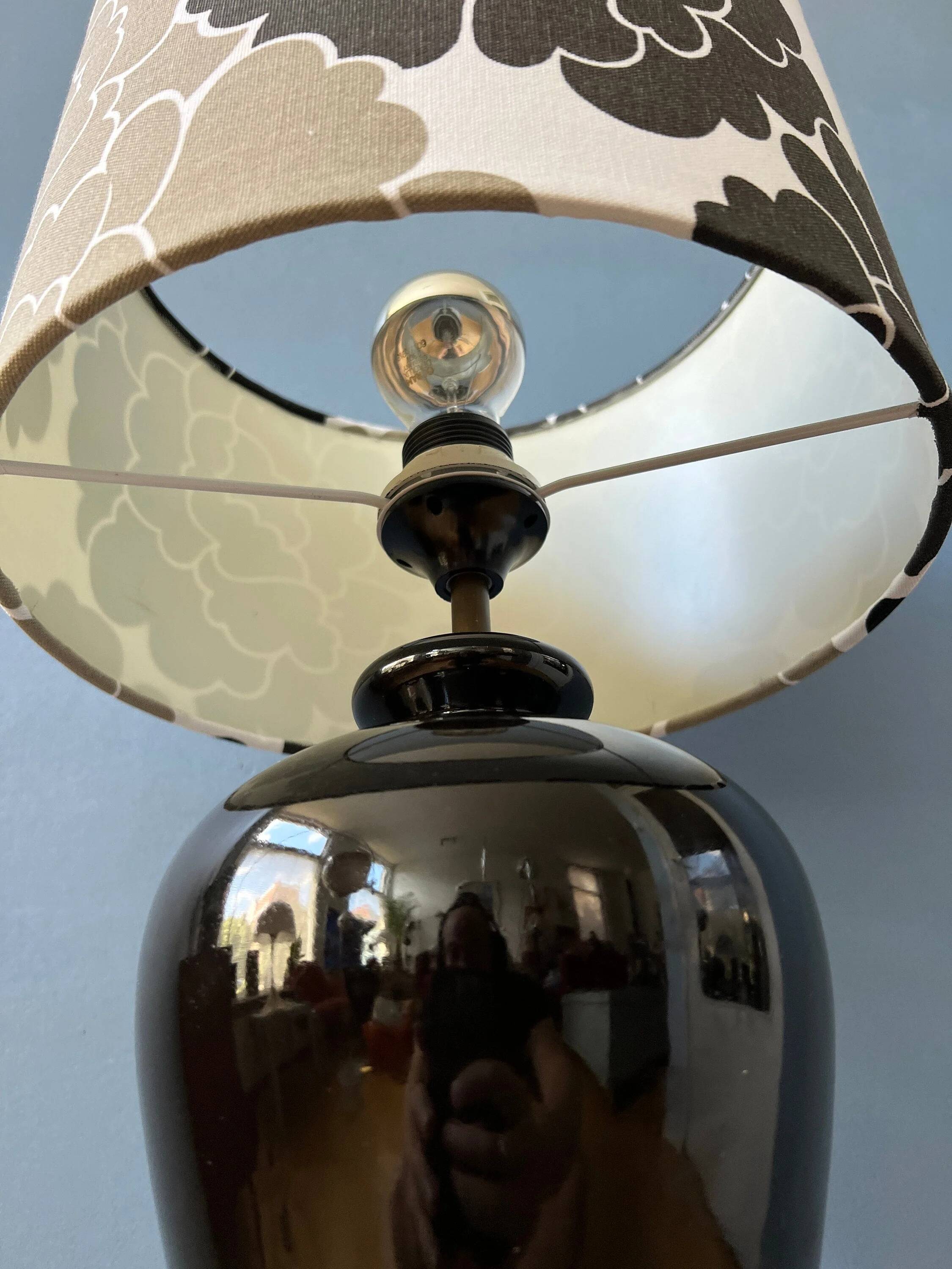 Small Space Age table lamp with a porcelain base and black and white flower shade.