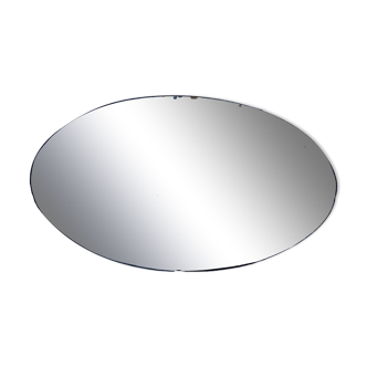 Beveled oval mirror stitched at the edges around the 1930